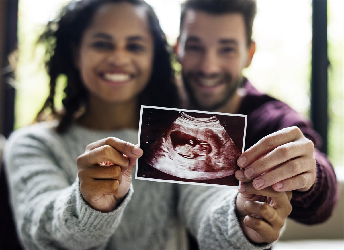 Expectant parents smiling as they hold their baby scan