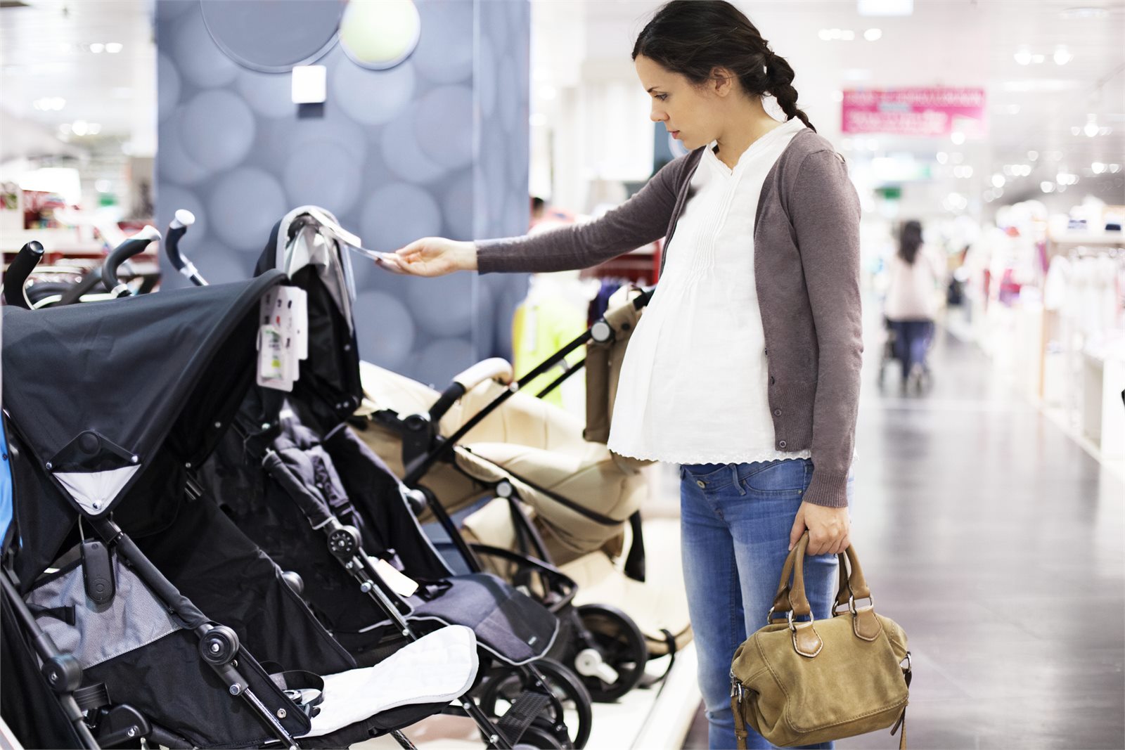 Expectant mother comparing pushchairs in a shop